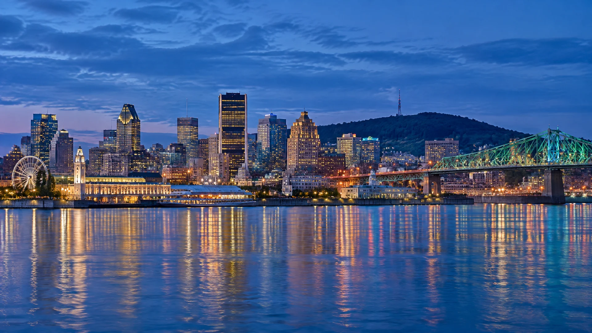 Montreal skyline, Mount Royal, and Jacques Cartier Bridge reflected in the Saint Lawrence River at blue hour